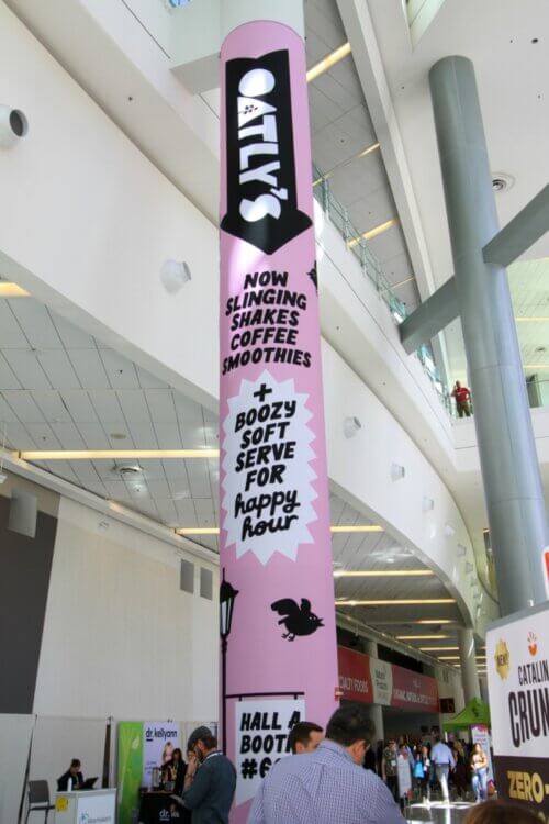Oatly's branded pillar wrap banner in a convention