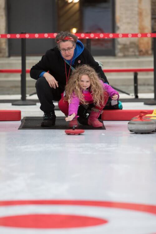 Grandmother teaching her daughter how curling works on target themed ice
