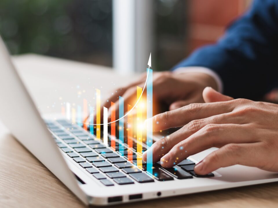 Person working on a laptop with an upward graph
