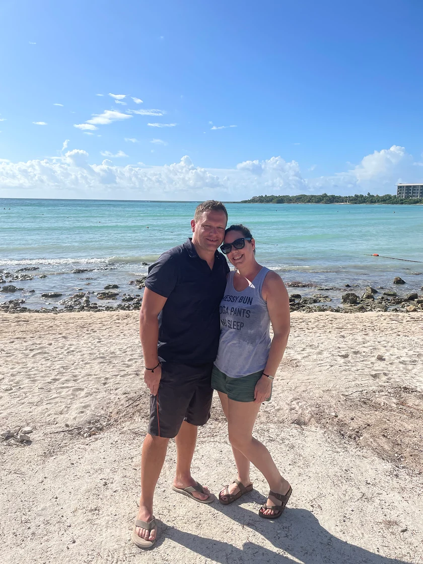 Rachel and her husband standing on a beach in Mexico