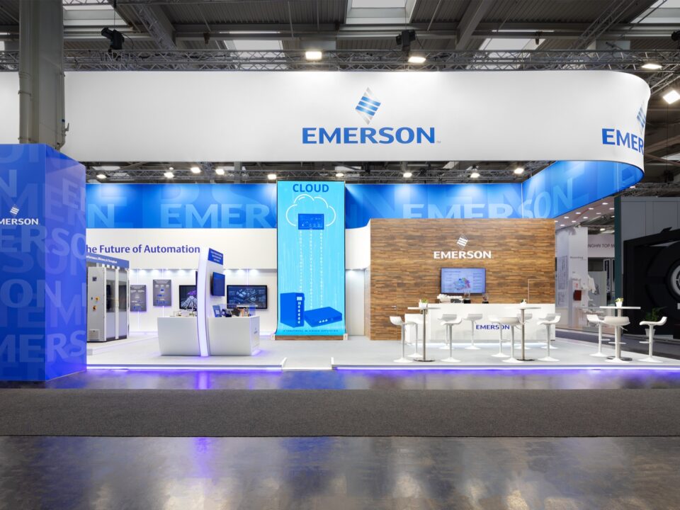 Image of Emerson exhibit with conversation tables, reception counter, and displays for product communication.