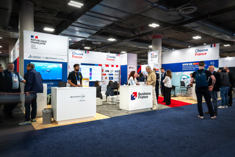 image of the CES 2025 Business France pavilion inside the trade show hall, featuring custom counters with representatives from French businesses, with branded walls behind them.