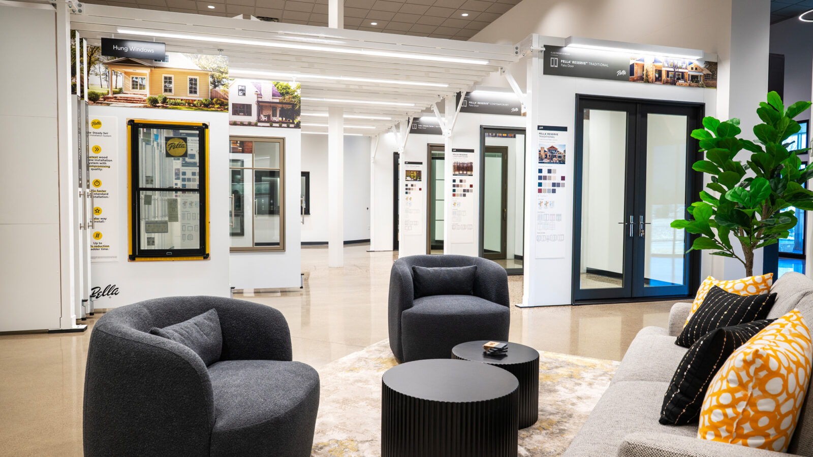 image from Pella Northland HQ, featuring Pella displays that are housed in the showroom space of the headquarters. These are custom built displays for Pella doors and windows, that are neatly hung next to each other and are able to roll out to view the product and information on offerings and customizations. There is a seating area for client meetings in the foreground.