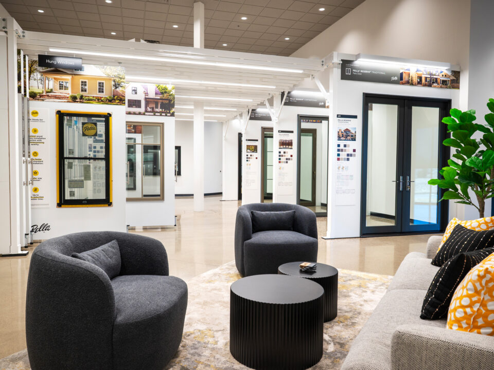 image from Pella Northland HQ, featuring Pella displays that are housed in the showroom space of the headquarters. These are custom built displays for Pella doors and windows, that are neatly hung next to each other and are able to roll out to view the product and information on offerings and customizations. There is a seating area for client meetings in the foreground.