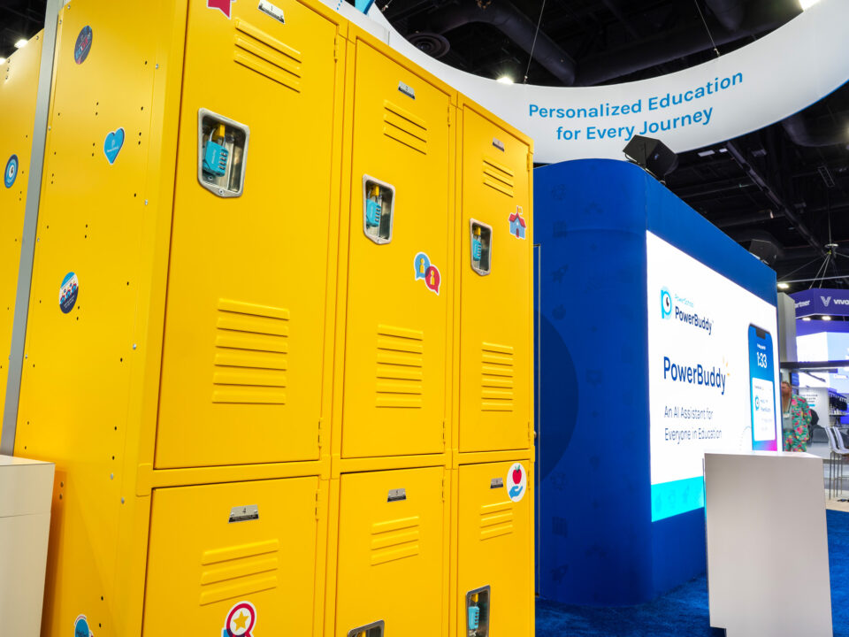2025 PowerSchool ISTE a close up of yellow lockers as part of the custom exhibit activation with giveaways inside, in the background, there is a large LED screen with the company's offerings displayed.